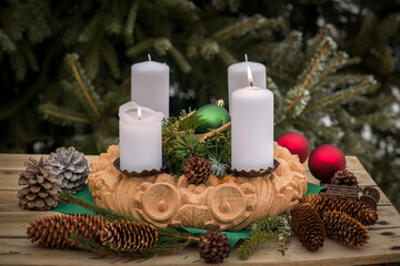 a beautiful handmade carved wooden advent wreath with christmas decoration on a wood table in the wintry garden