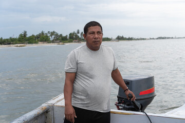 Fototapeta premium Man driving boat with outboard motor on tropical coast
