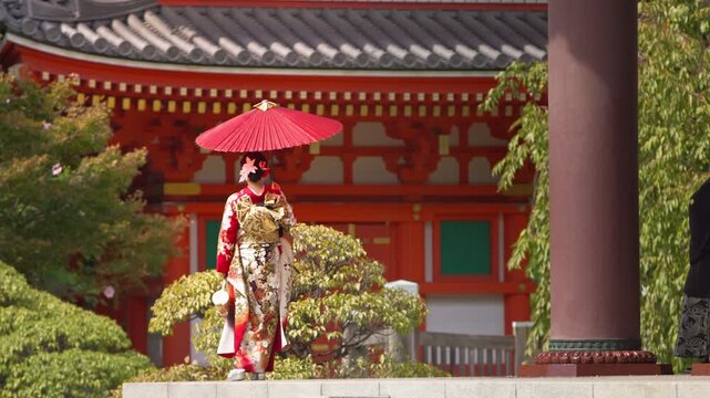 Slow motion view of a woman wearing traditional attire and holding a parasol as she walks past temple columns, emphasizing cultural heritage, warm tones and serene movement ideal for tourism