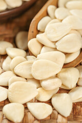 Sliced blanched almonds in wooden bowl on rustic wood background - healthy nuts ingredient