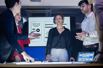 Diverse front-end developer and UX UI design team in a professional discussion over a complex web development project. Collaborating on the visual design and application strategy,