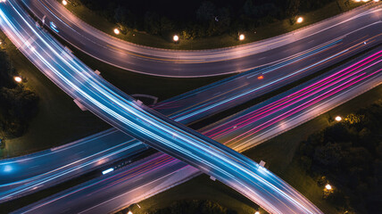 Aerial Top View of Multi Level Highway Interchange at Night with Blue White Traffic Light Trails City Transportation Infrastructure and Future Urban Mobility Concept