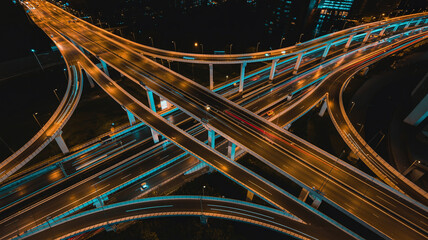 Aerial Top View of Multi Level Highway Interchange at Night with Blue White Traffic Light Trails City Transportation Infrastructure and Future Urban Mobility Concept