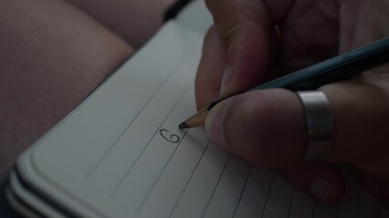 Close-up of a hand writing 2026 goals and resolutions on paper, with soft natural light and a simple desk setting.