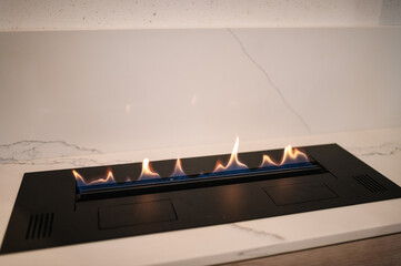 Obraz premium Automatic tabletop biofireplace. Burning eco bio ethanol fireplace built into white marble. Beautiful marble fireplace. Minimalist interior, alternative bio fireplot fireplace on ethanol gas.