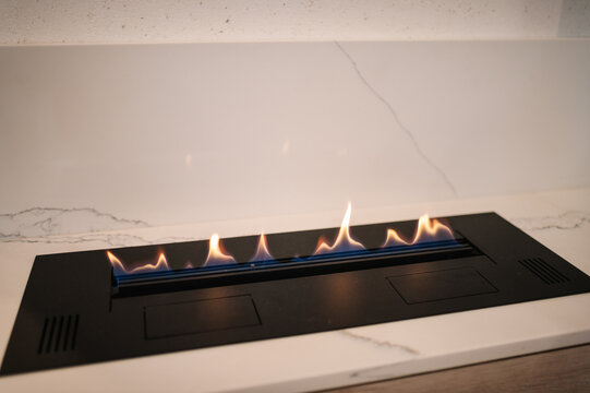Automatic tabletop biofireplace. Burning eco bio ethanol fireplace built into white marble. Beautiful marble fireplace. Minimalist interior, alternative bio fireplot fireplace on ethanol gas.