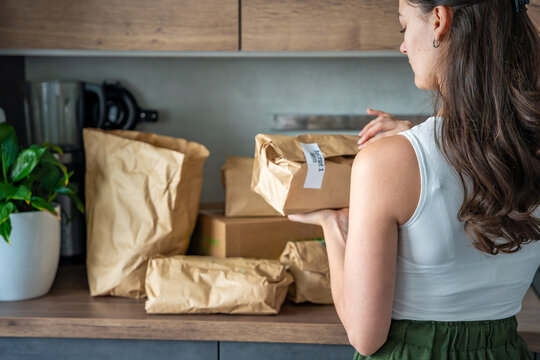 Woman holding a labeled grocery bag with the word Recept, meaning recipe in another language. Concept of convenient meal kit delivery with pre-portioned, ready-to-cook ingredients.