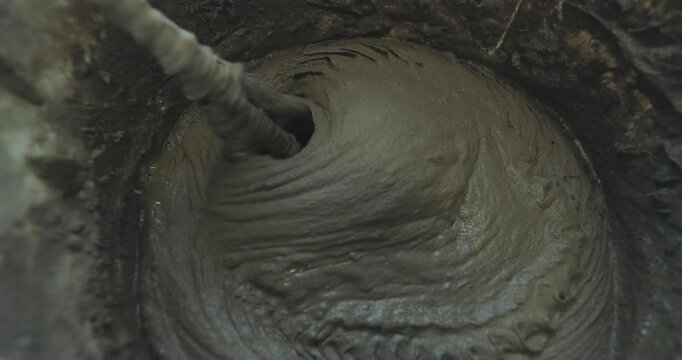A man mixes cement or adhesive mortar in a bucket using a paddle mixer or paddle drill. Mixing mortar for laying ceramic or porcelain tiles. Close-up