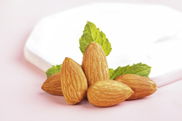 Fresh Shelled Almonds with Leaves on Pink Background
