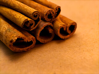 Close-up image of several cinnamon sticks resting on a brown textured background