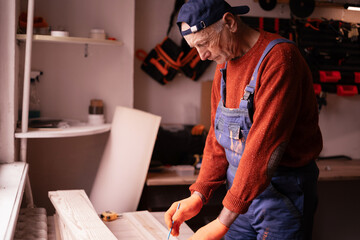 Profession, Small business and hobby concept. Senior elderly carpenter measuring wooden board using tools for work in workshop. Woodworker in carpenter shop