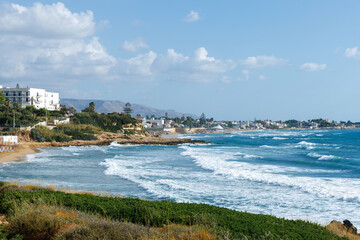 Italian Mediterranean coastline with beach hotels and mountains.