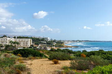 Fototapeta premium Sicily Italy seascape overlooking a turquoise bay and distant resort skyline.