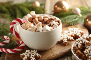 Tasty cocoa, marshmallows, candy canes, gingerbread cookies and Christmas decor on wooden table, closeup