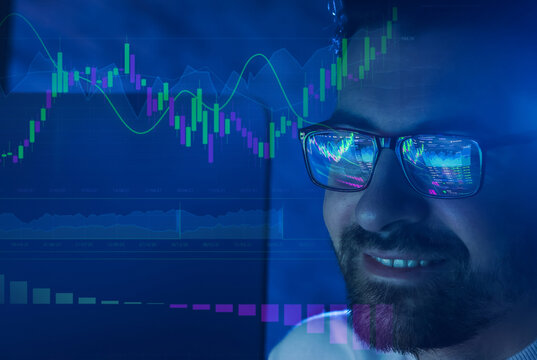 Stock trading data and graphs reflecting in man's glasses. Equity trader or financial analyst working on investment strategy - Powered by Adobe