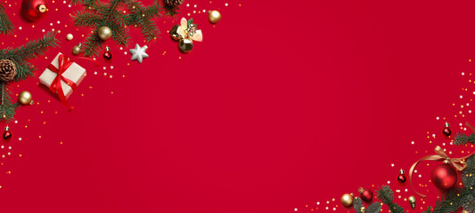 Christmas balls, gift box, fir branches and confetti on red background, top view. Greeting card or...