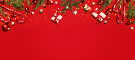 Christmas balls, gift boxes, fir branches and candy canes on red background, top view. Greeting...