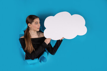 A young lady with a white poster in her hands on a blue background. Copy space