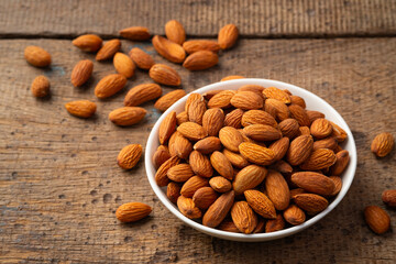 Dry roasted Almonds in white plate on wooden table.Heap of almond.