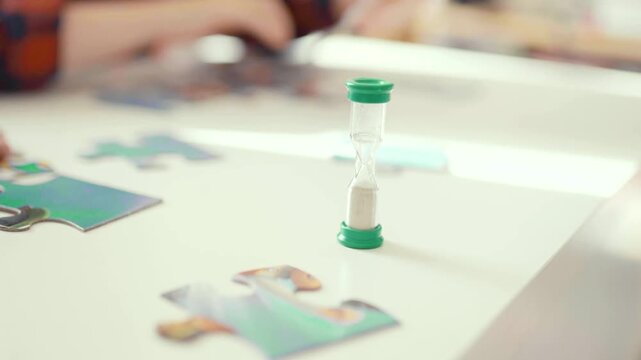 Child doing puzzle while sand clock is on at home.