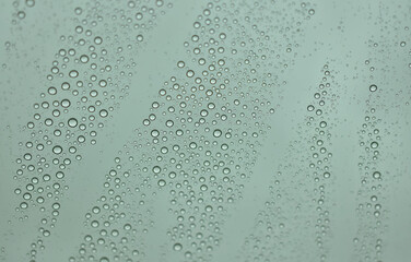 big raindrops, little raindrops, and medium raindrops. collected on the outside of a vehicle window creating unique designs and unique trails through the droplets
