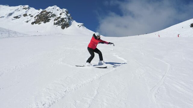Woman skiing on bright snow. Beginner skier practicing turns on mountain under clear sky. Skier rolls down with plow technic braking with skis and learns on snow slopes in bright winter sunlight