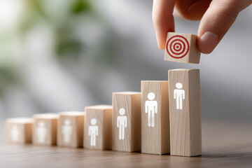 A hand places a marked block atop a progression of wooden blocks, symbolizing growth, success, and the ambition to reach personal and professional goals through effective leadership