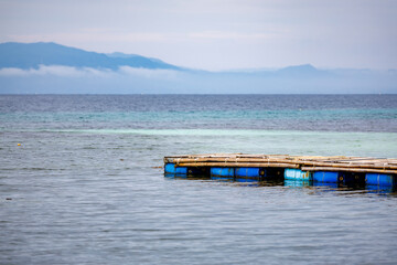 Handmade dock or fish cage platform floating near the shore, commonly used in island aquaculture...