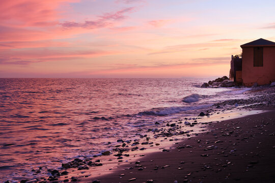 Pastel sunset over the Mediterranean Sea on the Spanish coast near Malaga with gentle waves and pebble beach foreground. - Powered by Adobe