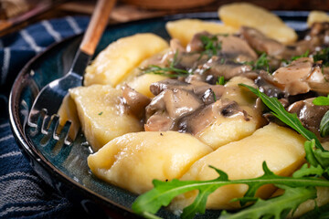 Homemade potato dumplings with mushrooms sauce and arugula.