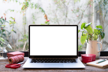 Laptop and red gift box and notebook and potted plant on wood desk