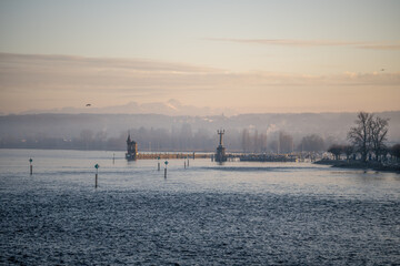 Lake Constance and Constance Harbor with snow-covered S&auml;ntis mountain in the background during a pastel-colored winter evening. Konstanz, Baden-W&uuml;rttemberg, Germany.
