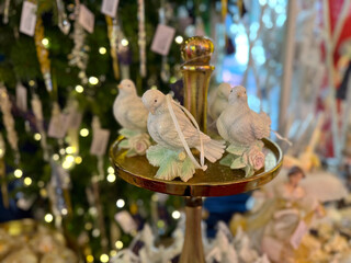 Fototapeta premium Decorative white doves displayed on golden stand with holiday ornaments