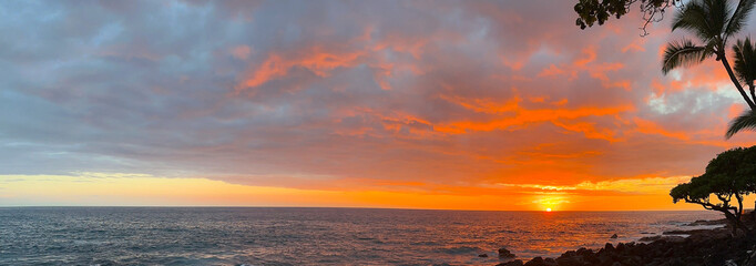 Fiery Pacific Ocean Sunset with Dramatic Clouds on the Volcanic Coast of the Big Island in Hawaii.