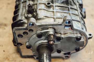 Disassembled old car gearbox with gears and tools on a workbench in an auto service garage. Repair, maintenance, and replacement of worn mechanical transmission parts in a vehicle.