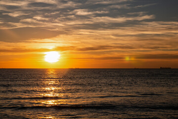 Obraz premium A stunning sunset over the sea with ships on the horizon and a peaceful atmosphere.