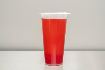 A plastic cup of sugary red lemonade served in a tall plastic cup