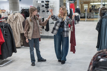 A mother and her teenage daughter are choosing a party dress at a shopping center.