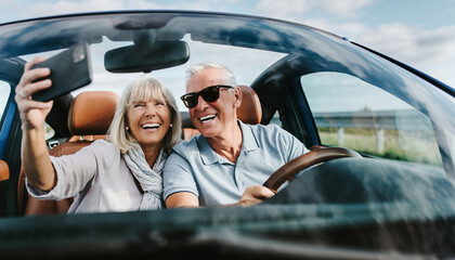 Para seniorów robiących sobie selfie podczas jazdy kabrioletem