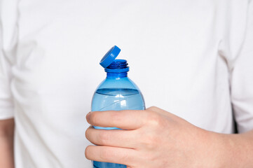 Close-up of a person holding a plastic bottle with a tethered cap, illustrating the EU’s new regulation requiring attached lids for improved recycling and reduced plastic waste.