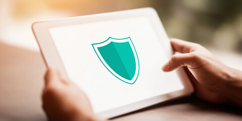 Hands holding a white tablet showing a shield icon, symbolizing internet security, privacy, and antivirus protection for devices