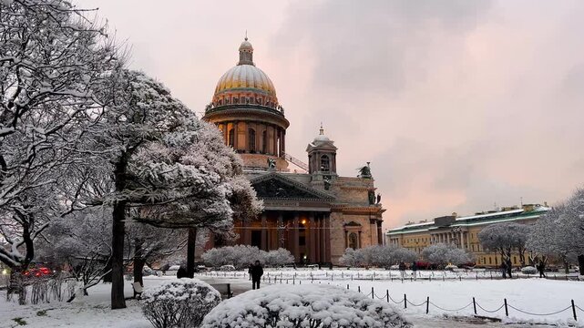 St. Petersburg, Russia - November 23, 2025: View of the snow-covered St. Isaac's Square with snow-covered trees and St. Isaac's Cathedral on a winter day at sunset. 4K