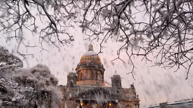 St. Petersburg, Russia - November 23, 2025: View of the snow-covered St. Isaac's Square with snow-covered trees and St. Isaac's Cathedral on a winter day at sunset. 4K