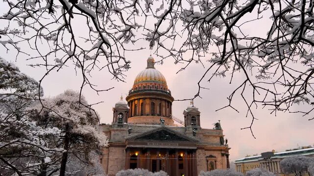 St. Petersburg, Russia - November 23, 2025: View of the snow-covered St. Isaac's Square with snow-covered trees and St. Isaac's Cathedral on a winter day at sunset. 4K