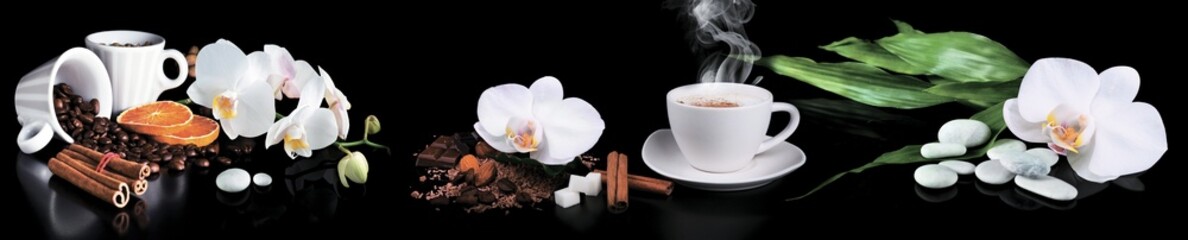 White orchids with coffee beans, cinnamon sticks, citrus slices and ceramic cups on a black reflective background