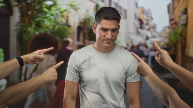 Man holding forehead while multiple hands point fingers at him on a busy city street, he seems to suffer a headache from the confrontation; shame social rejection.