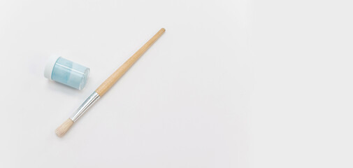 Flaconcino di tempera azzurra e pennello in legno e setole naturali su una superficie bianca