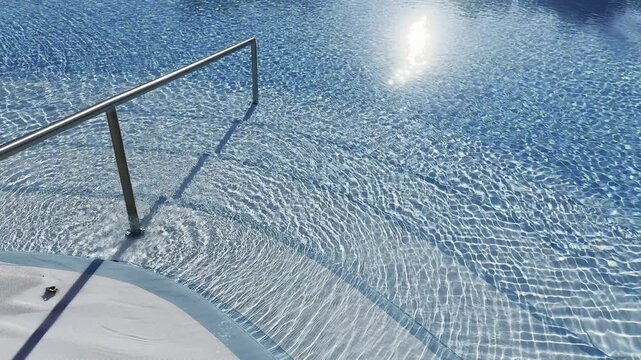 handrails by the pool with blue water on the background 