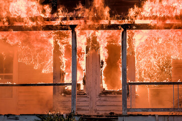 Double bay windows on a house porch being devoured by flames. A porch and windows on a residential...