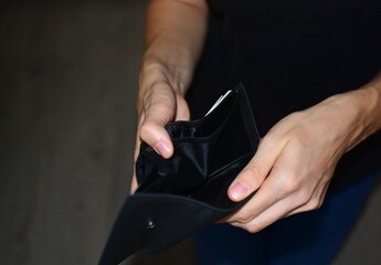 Person looking inside an empty wallet, showing financial problems, low savings, debt or lack of money. Concept of personal finance, poverty, budgeting and difficult economic situation.